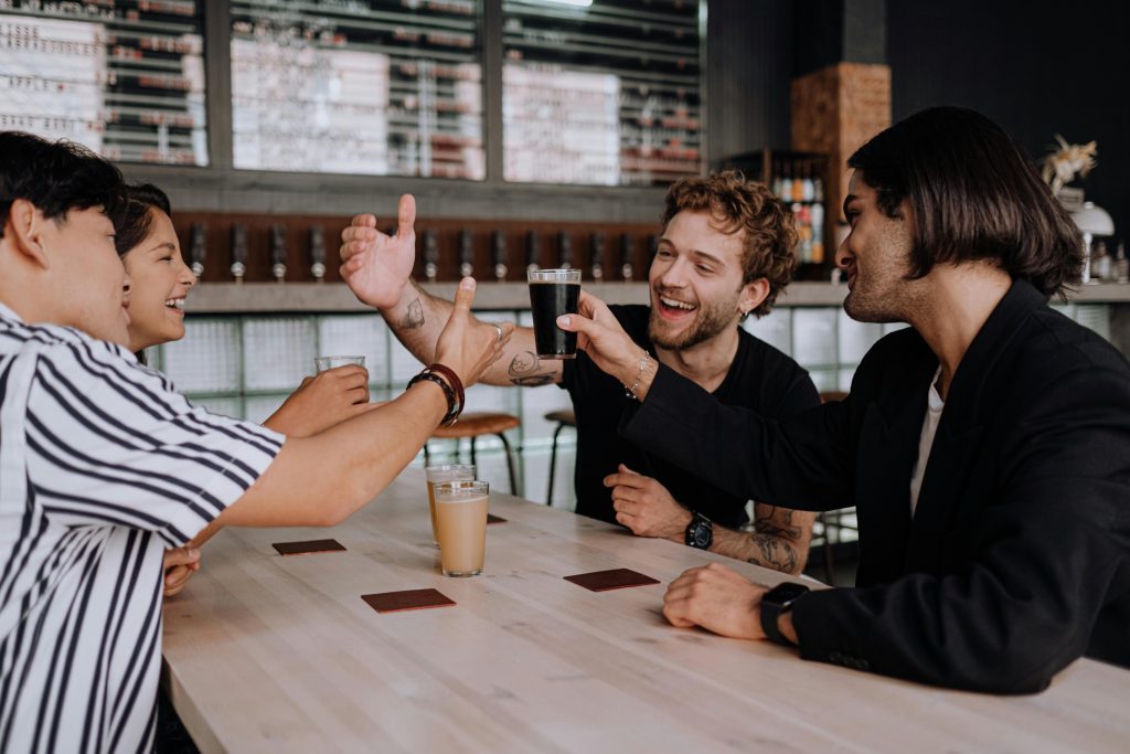 Group of friends cheerfully toasting drinks at a stylish indoor bar.